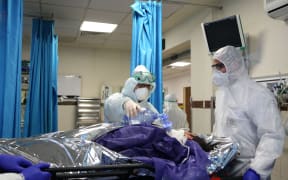 Ambulance staff wearing protective masks and suits bring in a patient to a hospital in Tehran, Iran on March 02, 2020.