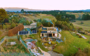 2019 drone view of our house showing solar panels, green roof, on-site-fuelled wood stove in use, chickens enclosure, some of the garden.