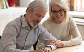 Stock image of happy older couple signing a legal document.