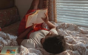 Teenager reading a book in bed.