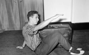 Brian Robson tried to mail himself from Australia to London in 1965. Brian shows how he sat with his suitcase in the packing case.