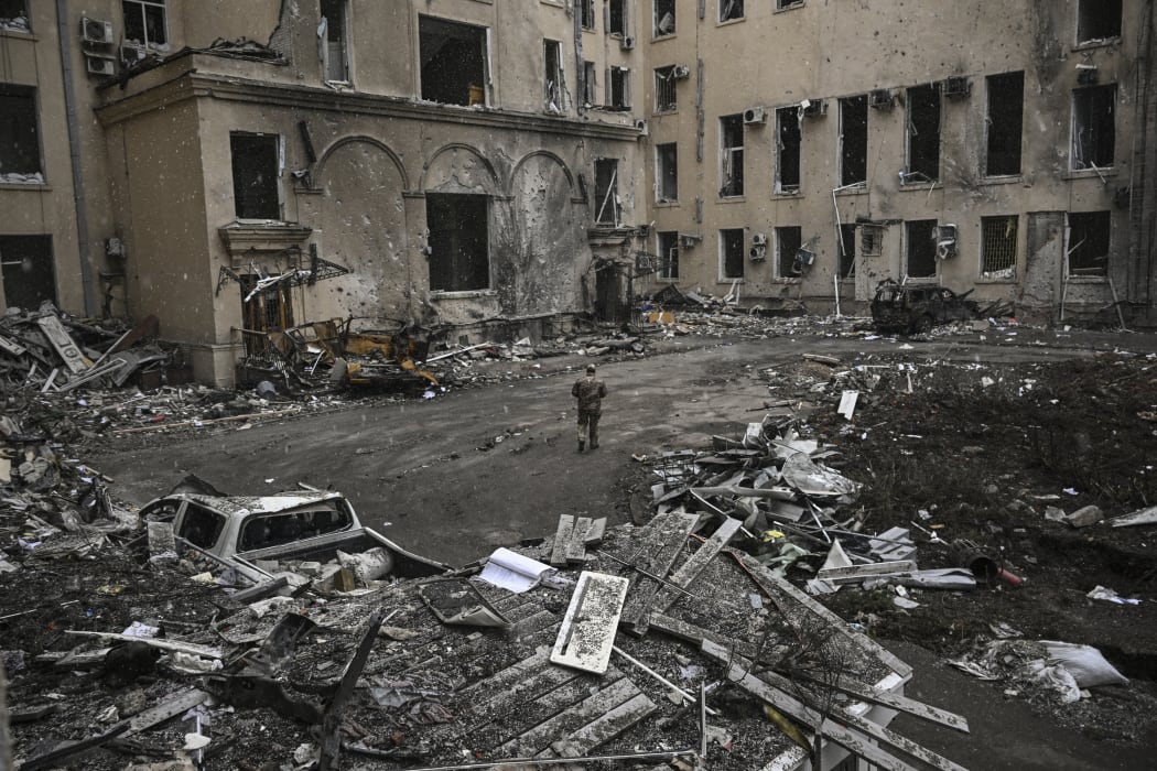A Ukranian serviceman walks toward the destroyed regional headquarters of Kharkiv, 27 March, 2022.
