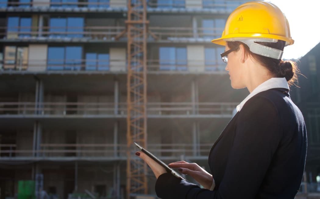 Female construction engineer/architect using tablet computer at construction site