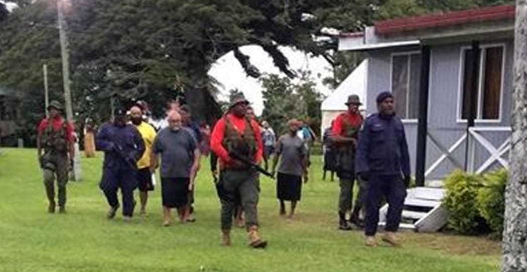 Ratu Epenisa Cakobau escorted by Police and armed military personnel.