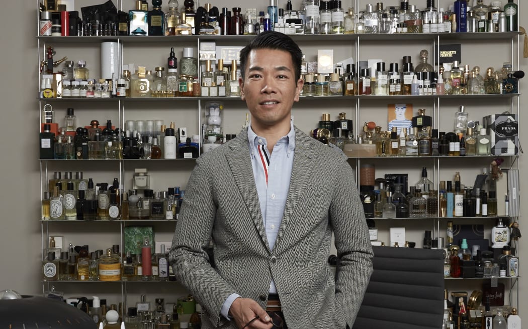 Christopher Yu standing with shelves behind him showcasing a massive collection of fragrances and candles.