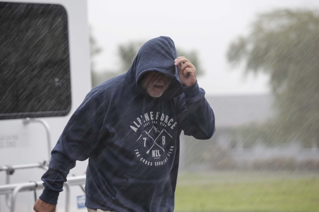 West Coast storm. A man struggles against wind and rain in Hari Hari.