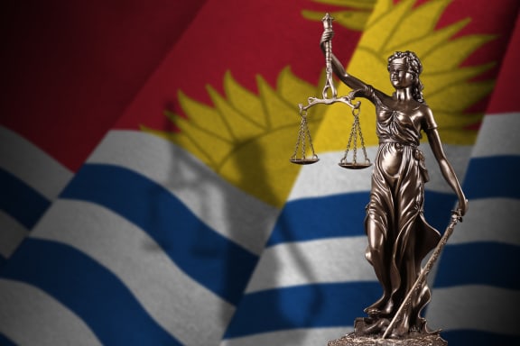 Kiribati flag with statue of lady justice and judicial scales in dark room. Concept of judgement and punishment, background for jury topics