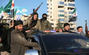 Anti-government fighters brandish their guns as they ride a vehicle in Syria's northern city of Aleppo on November 30, 2024. - Jihadists and their Turkish-backed allies breached Syria's second city of Aleppo on November 29, as they pressed a lightning offensive against forces of the Iranian- and Russian-backed government. (Photo by Omar HAJ KADOUR / AFP)