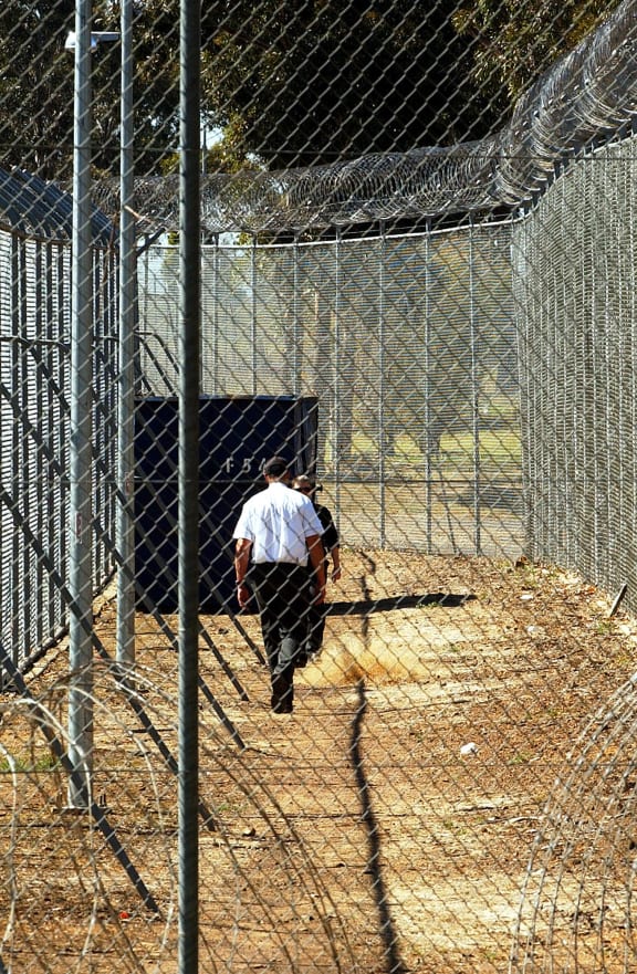 A Sept. 9, 2005 file photo of a guard walking inside the perimeter fence and razor wire that surrounds Villawood Detention Centre in Sydney.