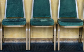 Green chairs lined up against a yellow wall in a waiting area