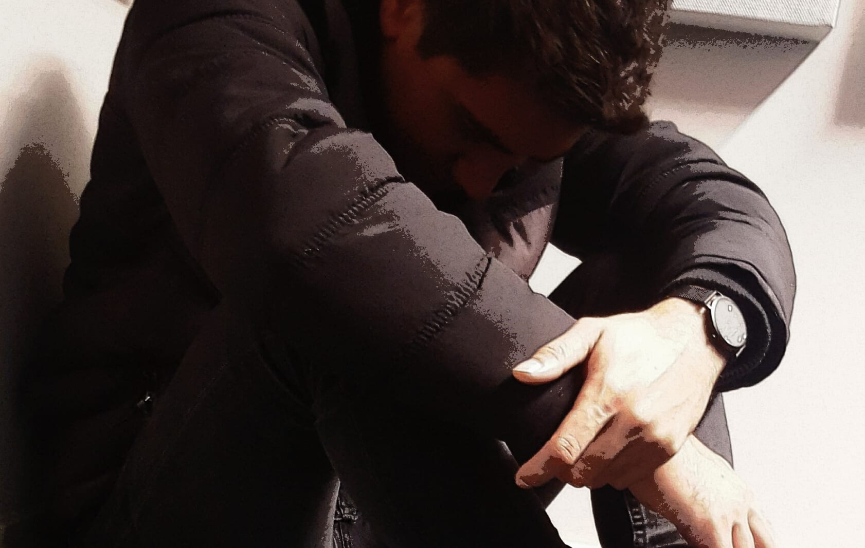 A staged photo of a young man hunched over, used to illustrate the use of seclusion rooms or mental health issues.