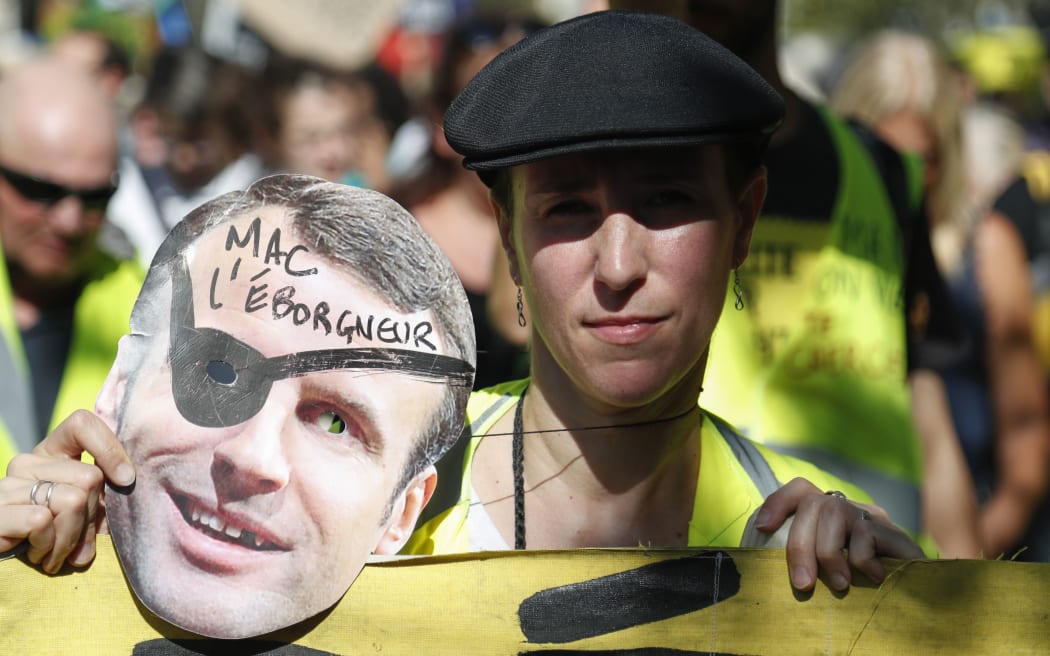 A protester poses with a cut-out of the French President during a Climate Change protest in Paris on September 21, 2019. The placard alludes to some protesters being blinded in one eye in previous clashes with riot officials