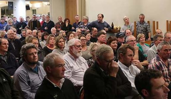Room crowded with people looking to front.