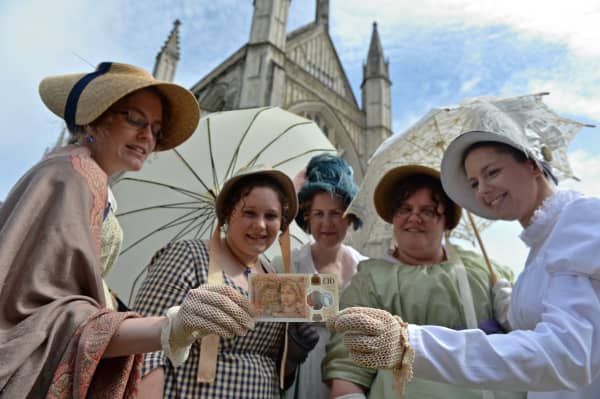 Jane Austen fans pose at Winchester Cathedral with a Bank of England £10 note featuring the author's portrait.