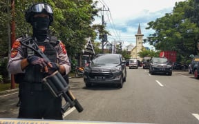 An Indonesian anti-terror policeman stands guard as police seal the area after an explosion outside a church in Makassar on March 28, 2021. (Photo by ANDI HAJRAMURNI / AFP)