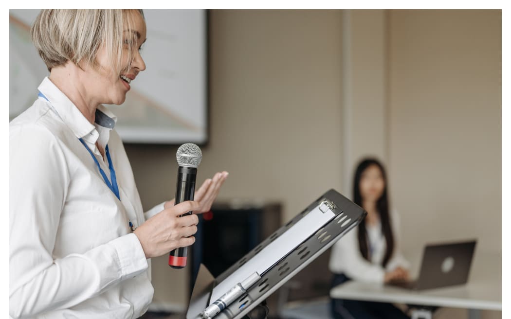 Woman holding microphone in front of a lectern