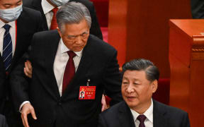China's President Xi Jinping (R) talks to former president Hu Jintao as he is assisted to leave from the closing ceremony of the 20th Chinese Communist Party's Congress at the Great Hall of the People in Beijing on October 22, 2022. (Photo by Noel CELIS / AFP)