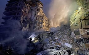 This handout picture taken and released by the Ukrainian Emergency Service on January 14, 2023, shows rescuers working on a residential building destroyed after a missile strike, in Dnipro. - A strike on a residential building in the eastern Ukrainian city of Dnipro on January 14, 2023, left at least five dead and 27 injured, officials said.