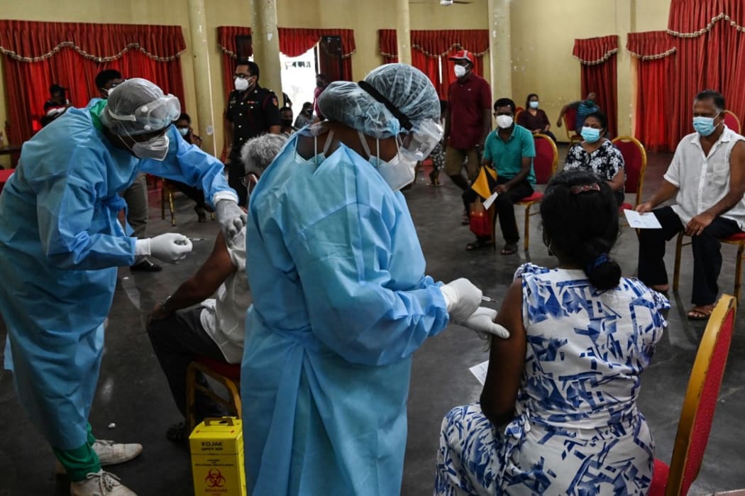 Health workers inoculate people with a dose of the Chinese-made Sinopharm Covid-19 coronavirus vaccine as government imposed travel restrictions and weekend lockdown to curb the spread of Covid-19 coronavirus, in Colombo on May 16, 2021.