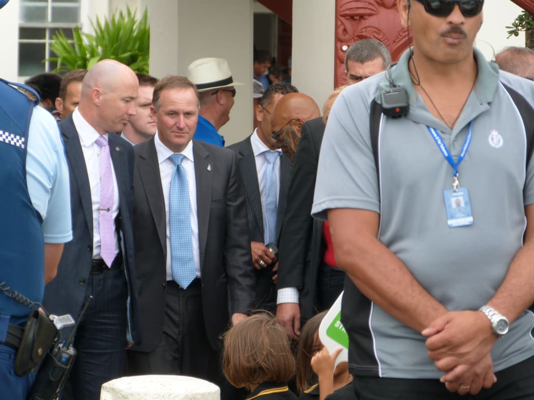 John Key leaves Te Tii Marae surrounded by security.