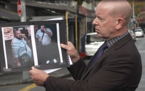 D.I Chris Barry holds up a photograph of an alleged offender involved in a homicide on Ponsonby Road.