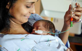 A mother tube feeds her premature baby