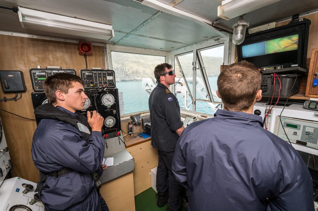 Members from the Royal New Zealand Navy Operational Dive Team monitor divers in the water from the 'Dive Shack' on board HMNZS Manawanui during training in Akaroa Harbour ahead of a search mission at the site of the FV Jubilee on 26 October 2015.