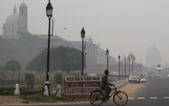 A man rides a bicycle along a street under heavy smog in New Delhi on October 29, 2019. (Photo by Jewel SAMAD / AFP)