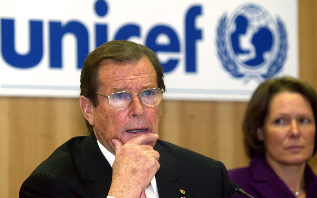 Sir Roger Moore, in his role as a UNICEF goodwill ambassador, speaks in 2003 as Christina Rau, wife of the German President at the time, looks on.