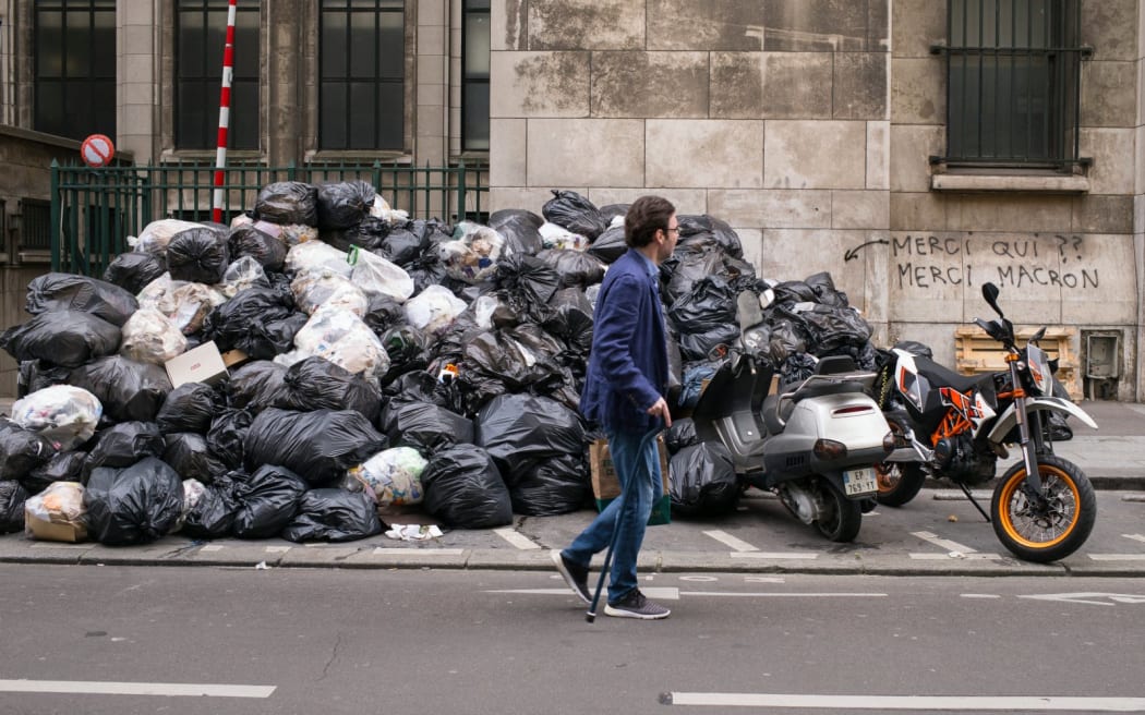 Garbage bins overflowing and garbage bags in a Paris street.