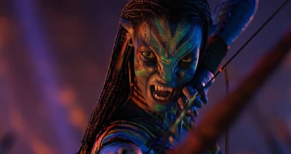 Neytiri has a multi-coloured face and a defensive snarl revealing sharp teeth.
