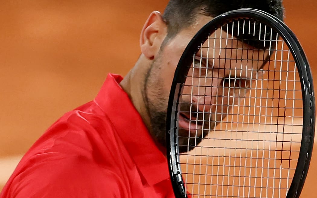 Serbia's Novak Djokovic looks on through his racket during his men's singles semi-final match against Italy's Jannik Sinner on day 13 of the French Open tennis tournament on Court Philippe-Chatrier at the Roland-Garros Complex in Paris on June 6, 2025. (Photo by Alain JOCARD / AFP)