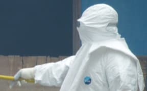 A healthcare worker burns infected items at a hospital in Monrovia, Liberia.