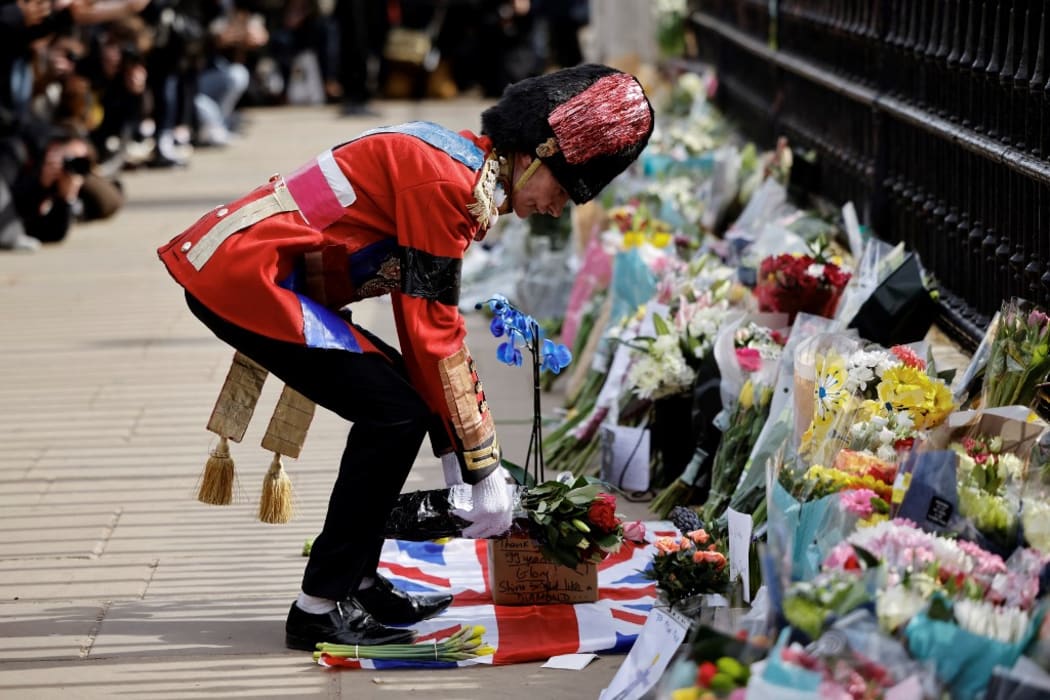 An ardent Royals fan lays a floral tribute at the front of Buckingham Palace in central London on April 9, 2021 after the announcement of the death of Britain's Prince Philip, Duke of Edinburgh.