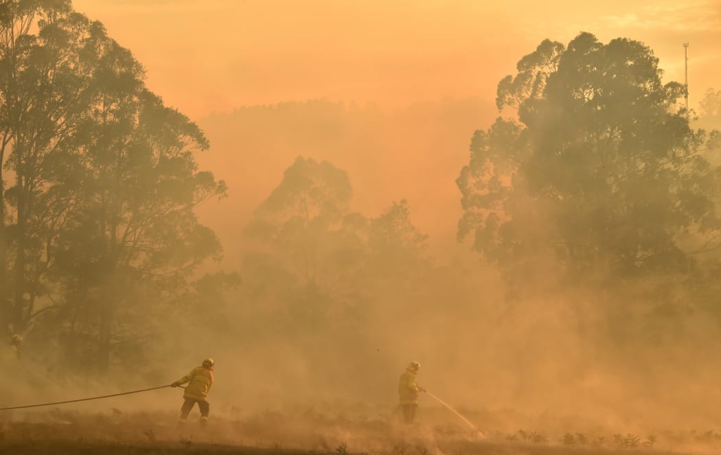 Firefighters defend a property from a bushfire at Hillville near Taree, 350km north of Sydney, on 12 November, 2019.