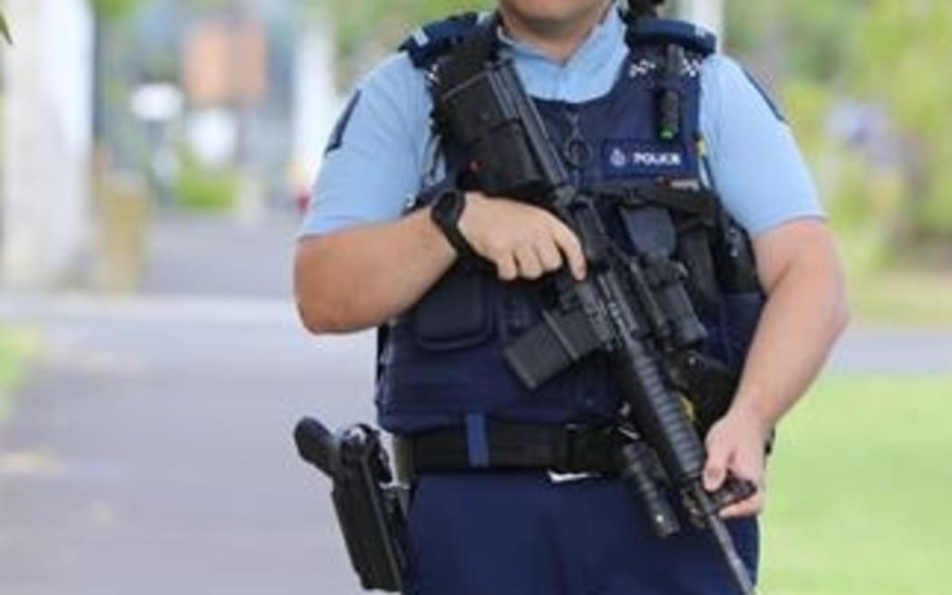 A police officer is seen carrying a rifle.