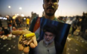 A supporter of Iraqi Shiite cleric Moqtada Sadr carries bullet casings and a spent shotgun shell in the capital Baghdad, on August 29, 2022.