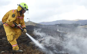 Fire fighter Lieutenant Oli Barnfather of the New Zealand Army fights an underground hotspot on the Port Hills of Christchurch.