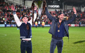 US actor and Wrexham owner Rob McElhenney (L) and US actor and Wrexham owner Ryan Reynolds (R) celebrate on the pitch with the National League trophy, 2023.