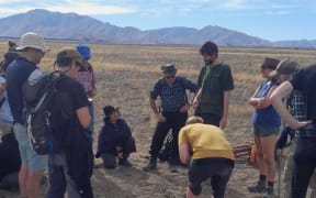 Searchers excitedly gather around the discovery.