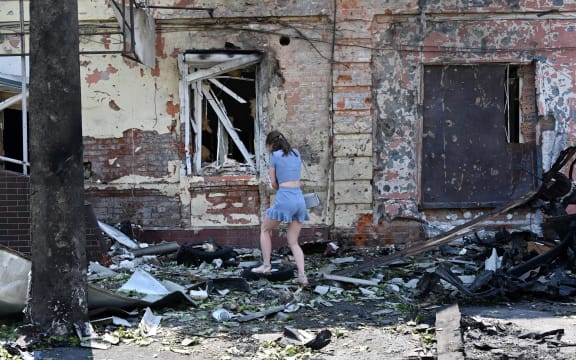 A woman stands among debris next to a recruitment centre building damaged after a drone attack in Kharkiv on 7 July, 2025, amid the Russian invasion of Ukraine.