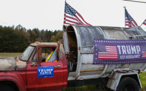 Chester Carter, 68, poses in his old garbage truck adorned with signs for Donald Trump he parked on a roadside in Stony Creek, Virginia, on November 1, 2024. (Photo by CHARLY TRIBALLEAU / AFP)