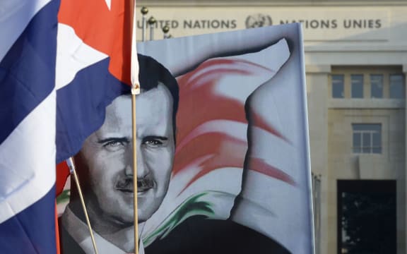 Pascal Simbikangwa.A portrait of President Bashar al-Assad and the Cuban flag outside the UN headquarters in Geneva.