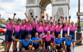 A group of riders of the 2021 Tour 21 raise their hands in the air in front of the Champs-Élysées after completing the Tour de France.