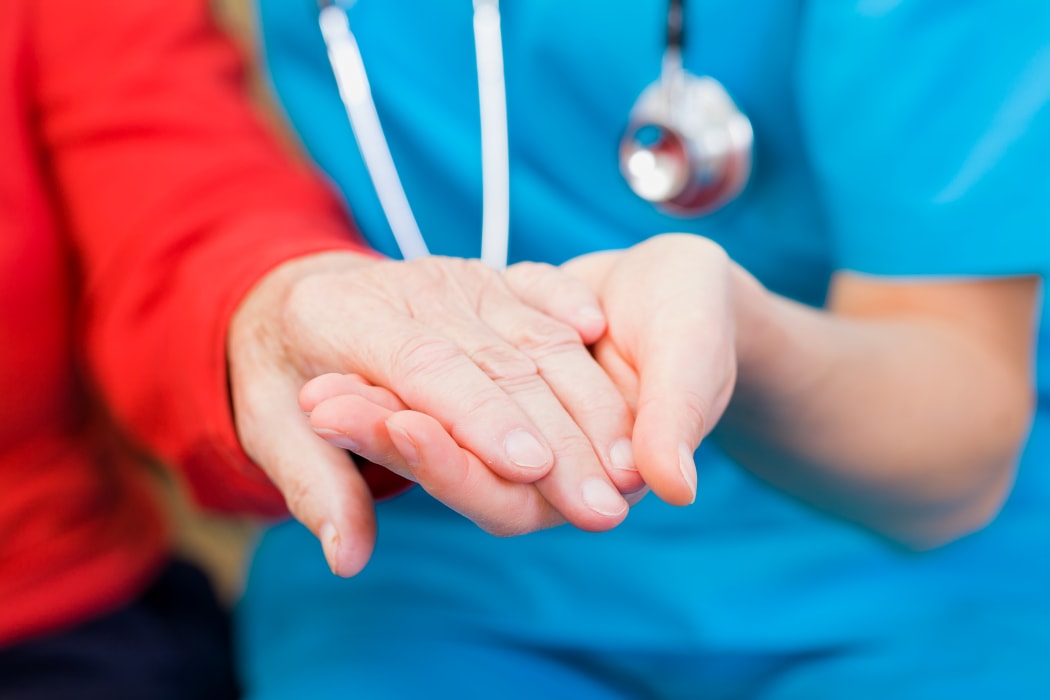 A doctor holds an elderly woman's hand