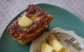A mini loaf of fry bread is buttered and sitting on a green plate.