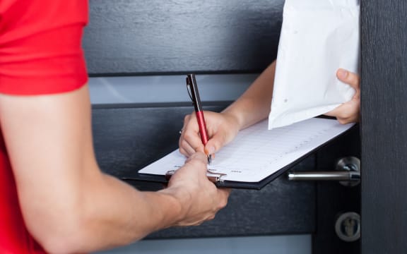 Woman signing parcel shipment documents on clipboard