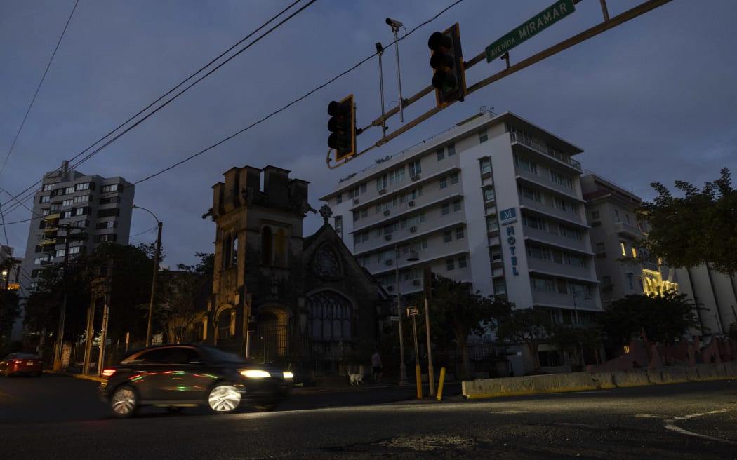 A car navigates through an intersection without stop lights in San Juan, Puerto Rico after a major power outage hit the island on December 31, 2024. - A major power outage plunged much of Puerto Rico into darkness Tuesday, with the US island territory's electric utility saying restoration could take up to two days. The "island-wide blackout" began at 5:30 am (0930 GMT), Luma Energy said in a social media statement. (Photo by Ricardo ARDUENGO / AFP)