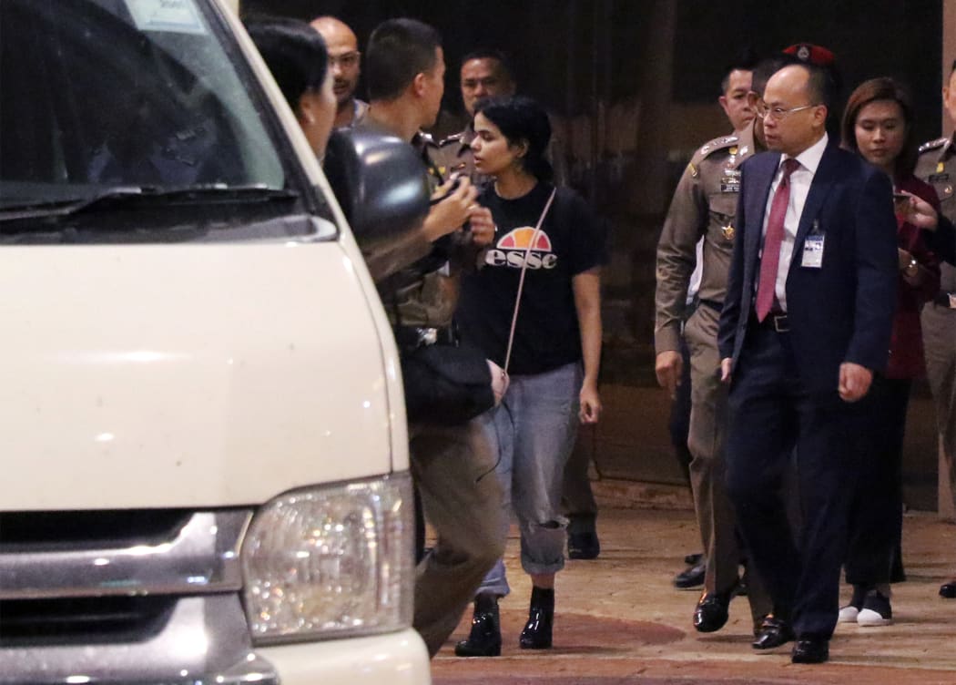 Eighteen-year-old Saudi woman Rahaf Mohammed al-Qunun (C) is escorted to a vehicle by a Thai immigration officer and United Nations High Commissioner for Refugees (UNHCR) officials at Suvarnabhumi international airport in Bangkok on January 7, 2019.