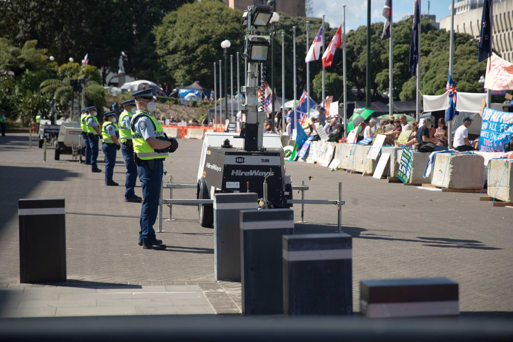 Anti-vaccine, anti-mandate protest in Wellington on Parliament grounds on 16 February 2022. Police standing on forecourt.